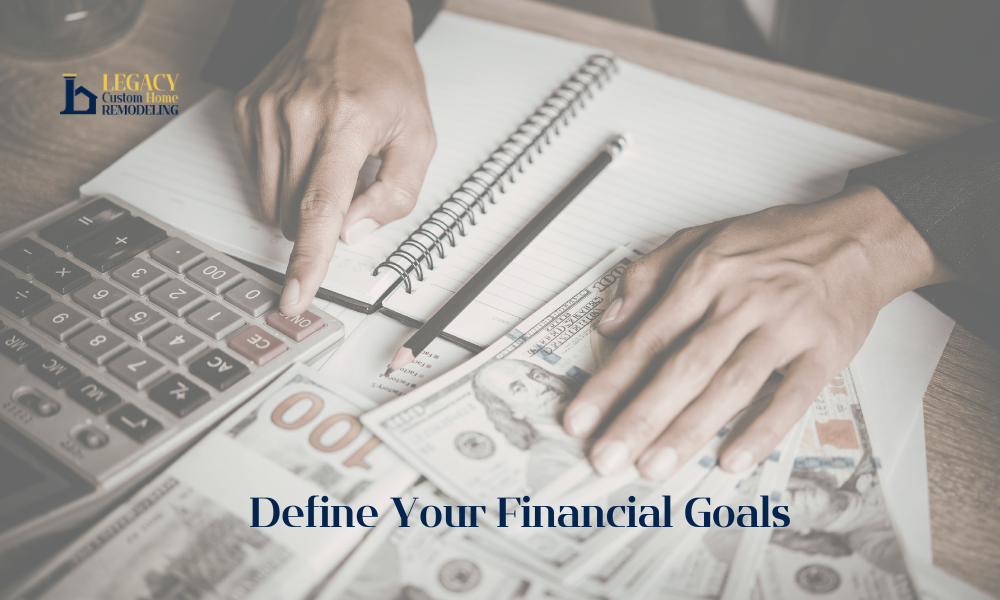 A person uses a calculator and writes in a notebook, surrounded by U.S. dollar bills on a desk. Text reads "Define Your Financial Goals." Logos show "Legacy Custom Home Remodeling." Atmosphere is focused and professional.